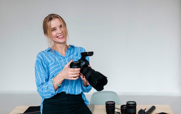 Donna di smiley in camicia blu che tiene una macchina fotografica