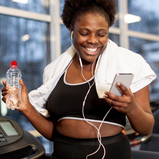 Donna di smiley in palestra utilizzando mobile