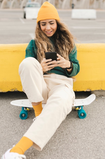 Donna di smiley su skateboard utilizzando il telefono