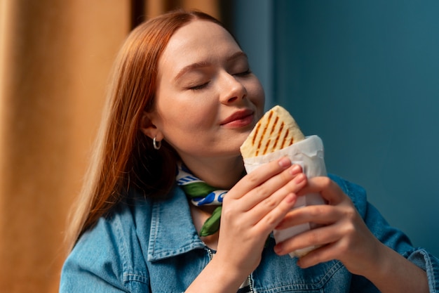 Donna di taglio medio con un panino avvolto in carta