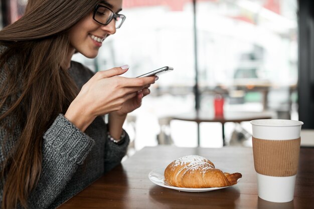 Donna di telefono utilizzando la caffetteria femminile