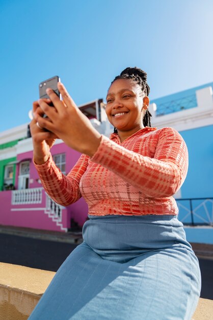 Donna di tiro medio che utilizza smartphone all'aperto