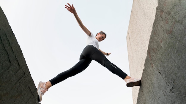 Donna di vista dal basso che parkouring su edifici