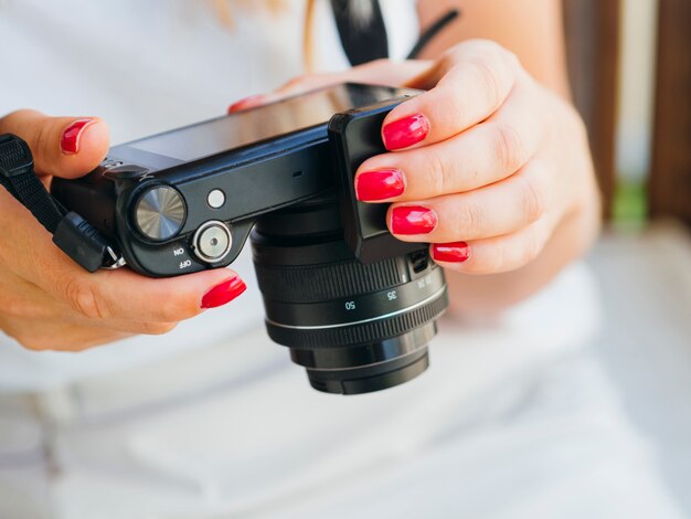 Donna di vista frontale che controlla il dispositivo della macchina fotografica