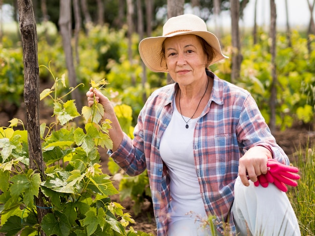 Donna di vista frontale che controlla il suo giardino