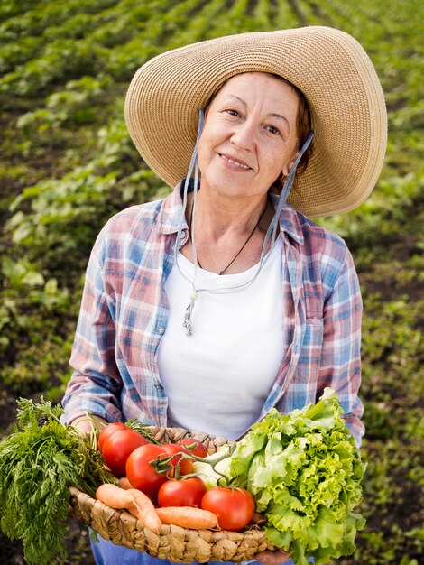 Donna di vista frontale che giudica un cestino pieno delle verdure