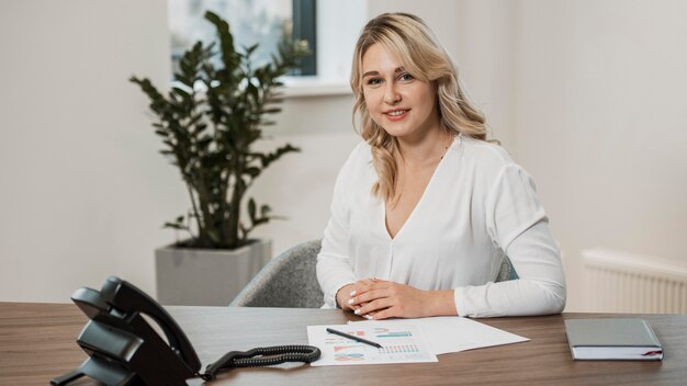 Donna di vista frontale che indossa una camicia bianca in ufficio