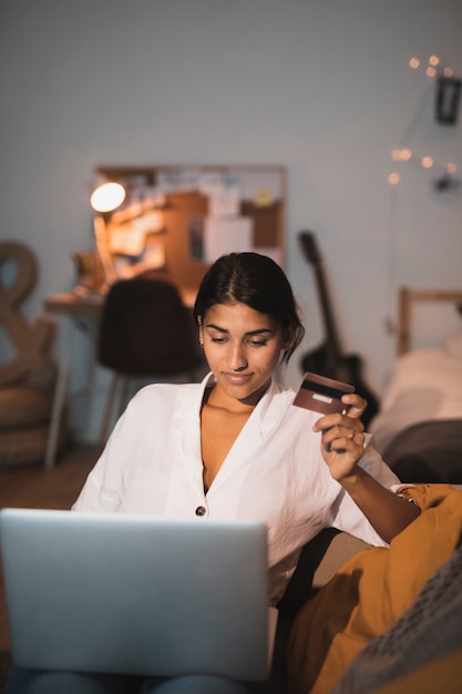 Donna di vista frontale che lavora al computer portatile e che tiene una carta