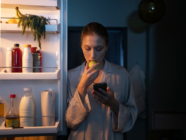 Donna di vista frontale che mangia spuntini di notte