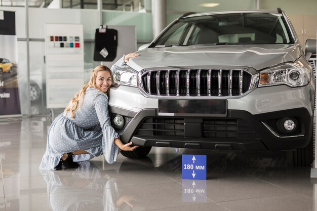 Donna di vista frontale che posa accanto ad un'automobile