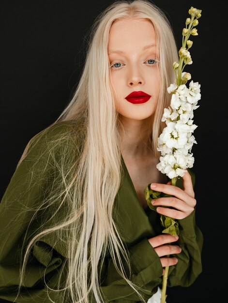 Donna di vista frontale che posa con il fiore