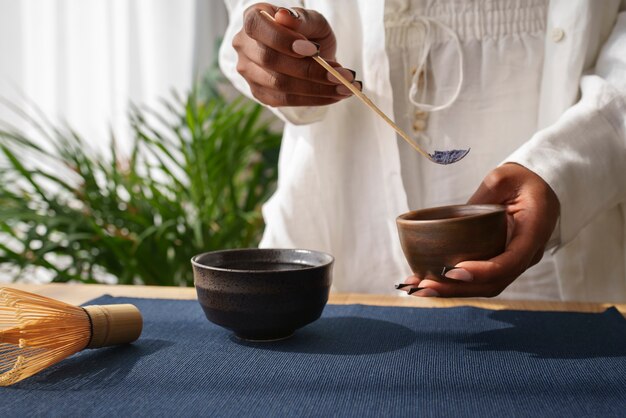 Donna di vista frontale che prepara matcha blu a casa