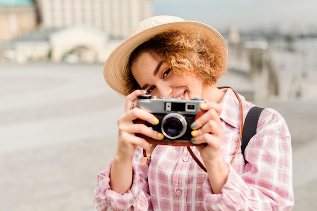 Donna di vista frontale che scatta una foto con una macchina fotografica durante il viaggio