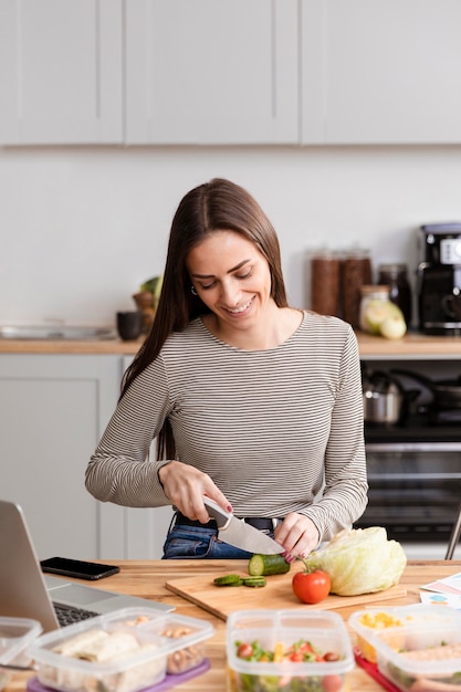 Donna di vista frontale che taglia la sua cena sul lavoro