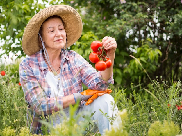 Donna di vista frontale che tiene alcuni pomodori in sua mano