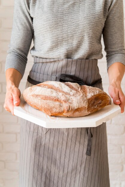 Donna di vista frontale che tiene bordo di legno con pane