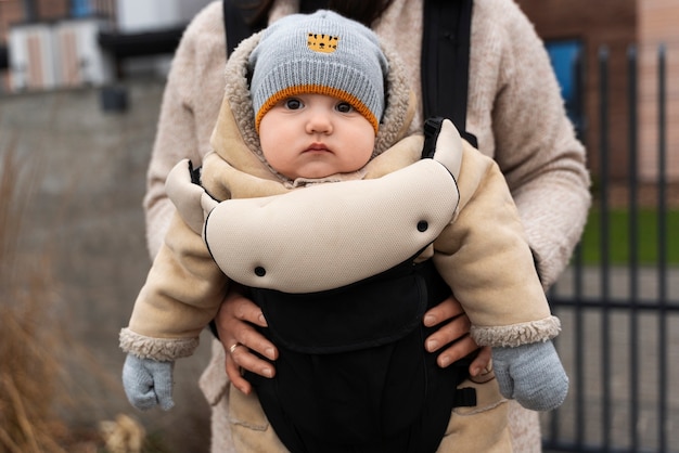 Donna di vista frontale che tiene il bambino nel marsupio