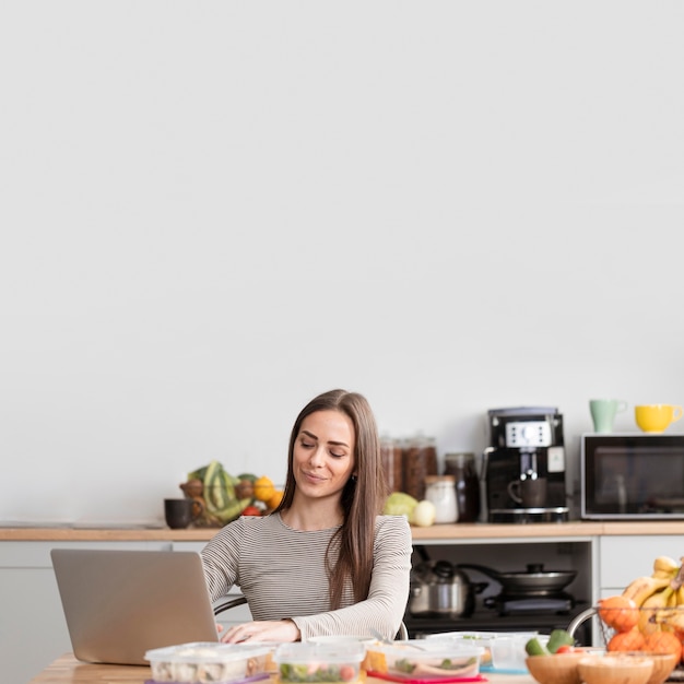 Donna di vista frontale con cibo e computer portatile