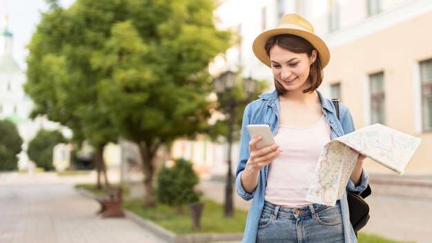 Donna di vista frontale con il cappello che controlla telefono cellulare