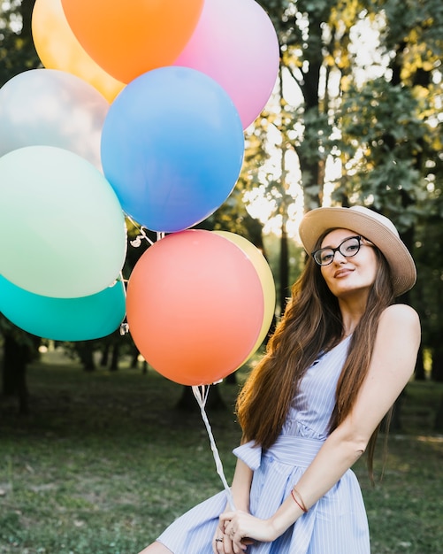 Donna di vista frontale con palloncini azienda cappello