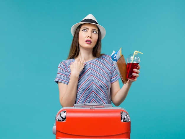 Donna di vista frontale in vacanza che tiene il succo con i biglietti sullo sfondo blu viaggio aereo femminile viaggio estivo mare
