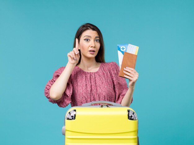 Donna di vista frontale in vacanza che tiene il suo portafoglio e biglietti su sfondo azzurro viaggio vacanza viaggio donna estate mare