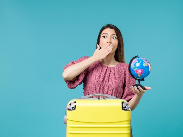 Donna di vista frontale in vacanza che tiene piccolo globo terrestre su sfondo azzurro mare vacanza viaggio viaggio donna estate