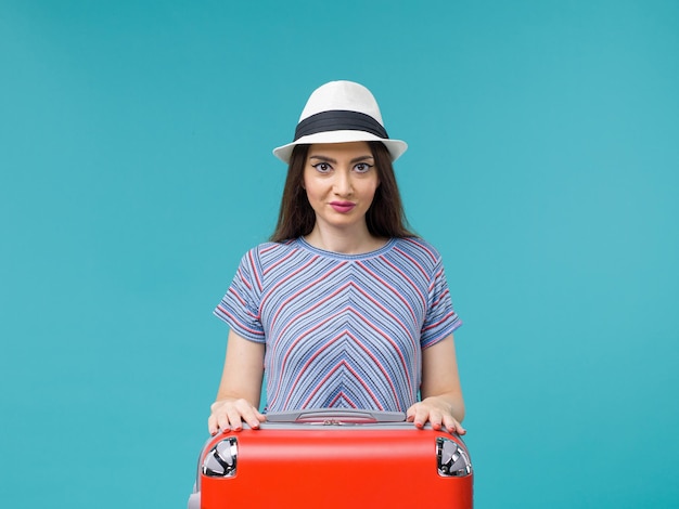Donna di vista frontale in vacanza con la sua borsa rossa che gode del suo viaggio sul viaggio femminile di vacanza di viaggio di viaggio del fondo blu