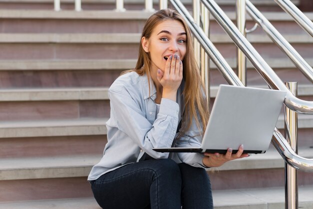 Donna di vista frontale sorpresa con il computer portatile