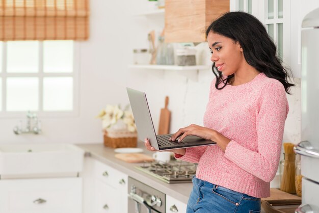 Donna di vista laterale a casa con il computer portatile