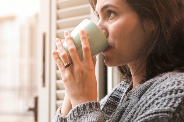 Donna di vista laterale che beve caffè