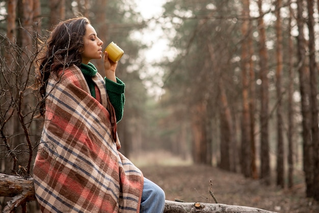 Donna di vista laterale che gode della tazza di tè in natura