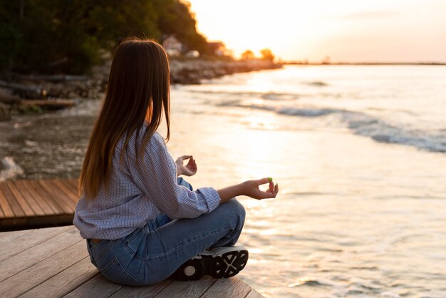 Donna di vista laterale che guarda il mare al tramonto con lo spazio della copia