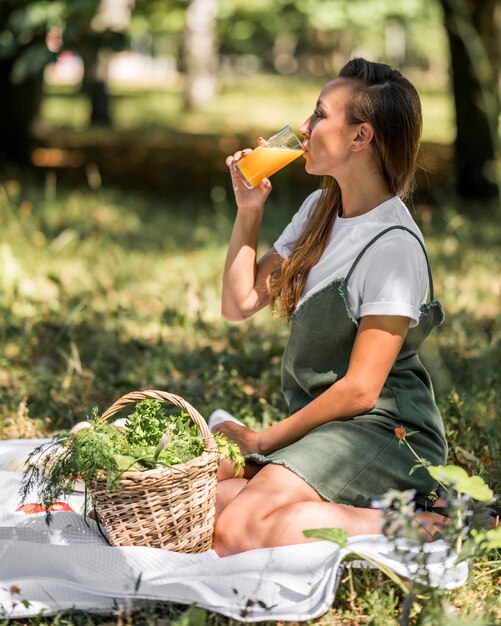 Donna di vista laterale che ha un picnic con spuntini sani