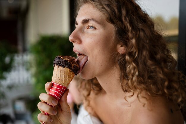 Donna di vista laterale che lecca il cono gelato