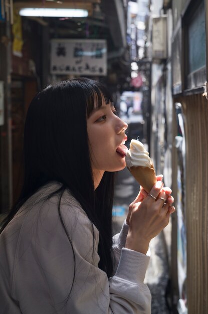 Donna di vista laterale che lecca il cono gelato