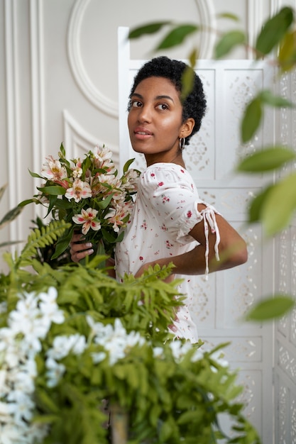 Donna di vista laterale che posa con i fiori