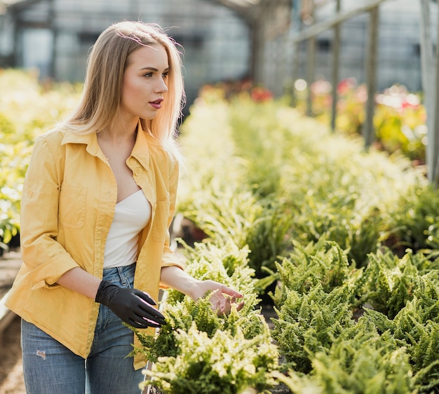 Donna di vista laterale che prende cura dei fiori