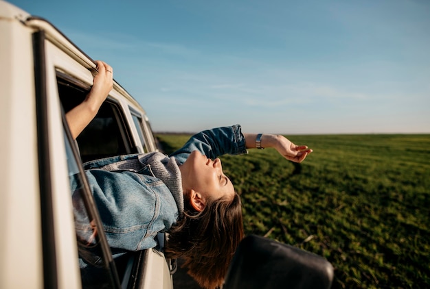 Donna di vista laterale che rimane con la testa fuori da un furgone