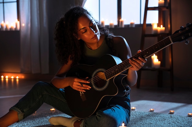 Donna di vista laterale che suona la chitarra