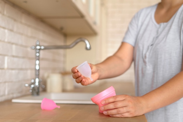 Donna di vista laterale che tiene tazza mestruale