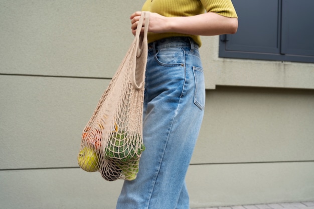 Donna di vista laterale che trasporta generi alimentari in borsa