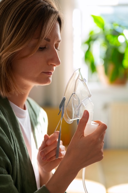 Donna di vista laterale che utilizza il nebulizzatore