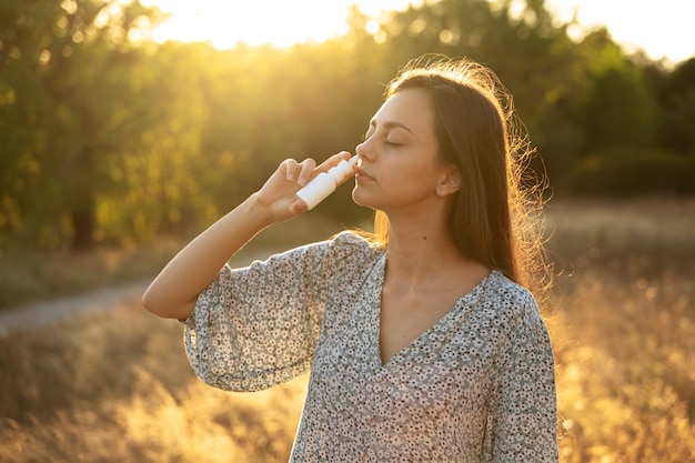 Donna di vista laterale che utilizza spray nasale