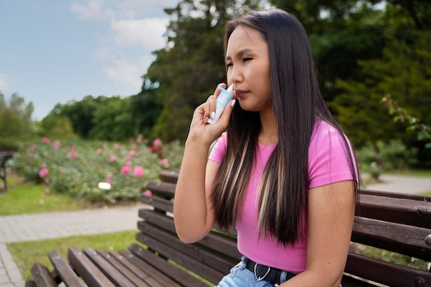 Donna di vista laterale che utilizza spray nasale