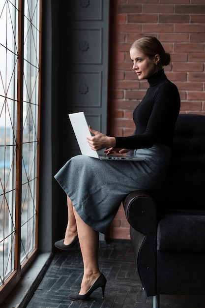 Donna di vista laterale con il computer portatile