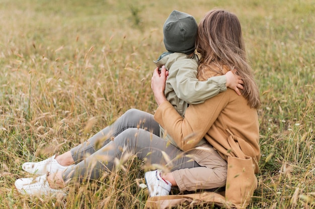 Donna di vista posteriore che abbraccia suo figlio