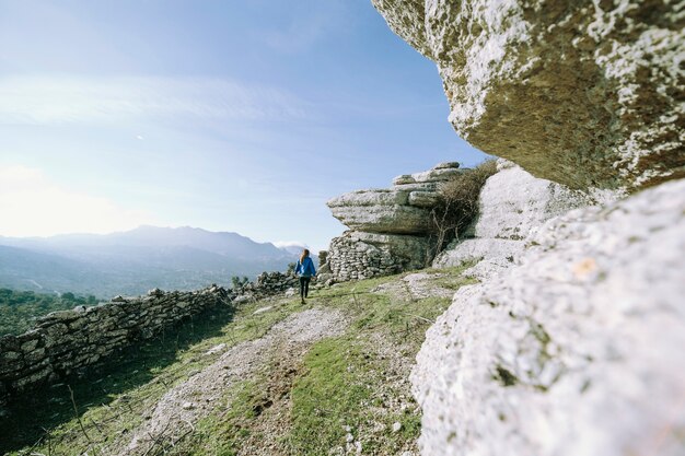 Donna di vista posteriore che cammina vicino alle rocce