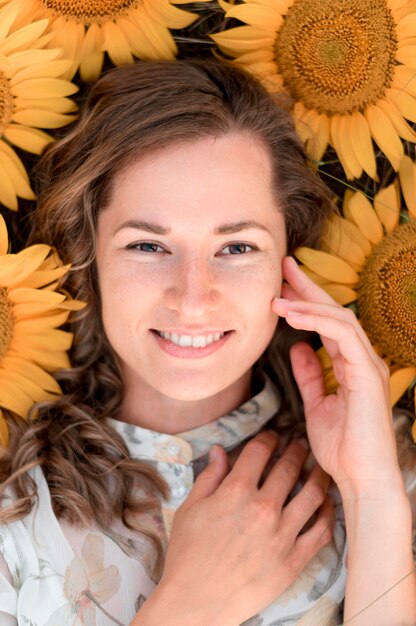 Donna di vista superiore che posa nel campo di girasole