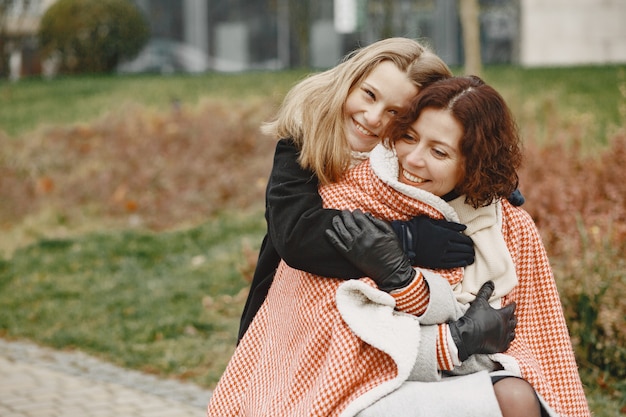 Donna disabile in sedia a rotelle con la figlia. Famiglia che cammina fuori al parco. La bambina ha coperto sua madre dal plaid.